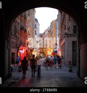 Ein Bogen führt zu einer lebhaften Dämmerungsstraße in Lyon, Frankreich. Stockfoto