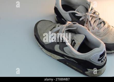 Ein Foto von einem Paar schmutzig weißen Nike Air Max 90 Läufern auf einer weißen Oberfläche. Stockfoto