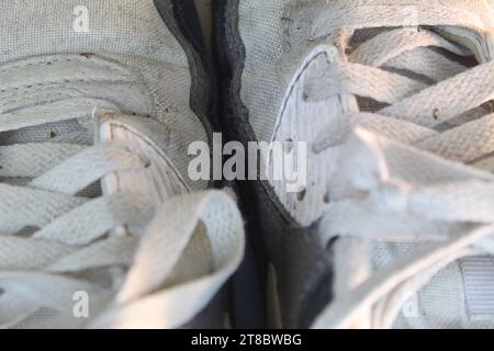 Ein Nahfoto der Schnürsenkel der weißen, dreckigen Nike Air Max 90 Läufer auf einem weißen Schreibtisch. Stockfoto