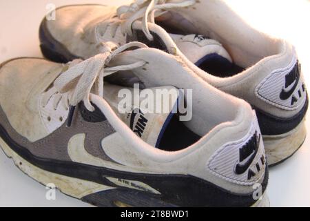 Ein Foto von einem Paar schmutzig weißen Nike Air Max 90 Läufern auf einer weißen Oberfläche. Stockfoto