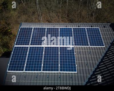 Erleben Sie die Stärke der Solartechnologie auf einem robusten Dach, das aus der Luftperspektive einer Drohne erfasst wird. Zehn Photovoltaik-Panels stehen stolz Stockfoto