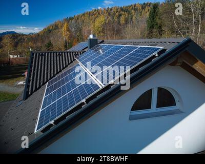 Halten Sie den herbstlichen Charme mit dieser Drohnenaufnahme fest, die die Seitenansicht von PV-Panels auf dem dunklen Dach einer privaten Residenz zeigt. Vor dem Hintergrund von Stockfoto