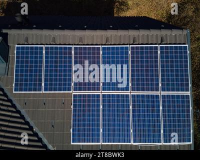 Erleben Sie die Stärke der Solartechnologie auf einem robusten Dach, das aus der Luftperspektive einer Drohne erfasst wird. Zehn Photovoltaik-Panels stehen stolz Stockfoto