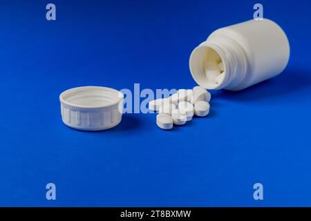 Nahaufnahme einer Gruppe weißer Tabletten mit einer verschreibungspflichtigen Flasche im Hintergrund. Stockfoto