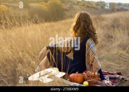 Die schöne junge Musikerin spielte die Melodie auf der Akustikgitarre und entspannte sich, saß auf dem Feld und genoss den Sonnenuntergang im Herbst. Picknick Im Freien. Roma Stockfoto