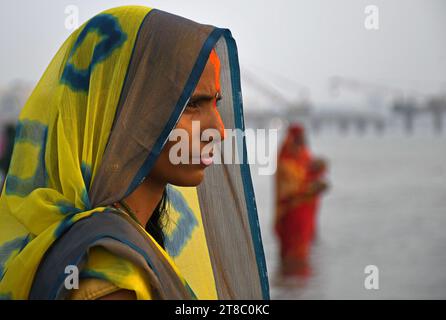 Eine Hindu-Frau beobachtet die untergehende Sonne anlässlich von Chhath Puja am Strand in Mumbai. Chhath Puja wird von den Menschen aus den nordstaaten Indiens gefeiert. Die Gläubigen versammeln sich in der Nähe eines Wasserkörpers, führen Rituale durch und beten zur untergehenden Sonne am Abend und zur aufgehenden Sonne. Am nächsten Morgen danken sie ihm für das Leben auf der Erde. Stockfoto