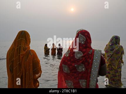 Mumbai, Indien. November 2023. Hindufrauen, die im Wasser stehen, beten zur untergehenden Sonne anlässlich von Chhath Puja am Strand in Mumbai. Chhath Puja wird von den Menschen aus den nordstaaten Indiens gefeiert. Die Gläubigen versammeln sich in der Nähe eines Wasserkörpers, führen Rituale durch und beten zur untergehenden Sonne am Abend und zur aufgehenden Sonne. Am nächsten Morgen danken sie ihm für das Leben auf der Erde. (Foto: Ashish Vaishnav/SOPA Images/SIPA USA) Credit: SIPA USA/Alamy Live News Stockfoto