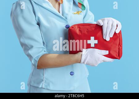 Großaufnahme einer eleganten Lufthochfrau auf blauem Hintergrund in blauer Uniform mit Verbandskasten. Stockfoto