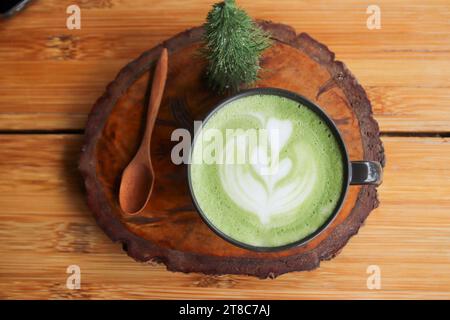 Tasse grüner Milchtee auf einem Holzständer Stockfoto