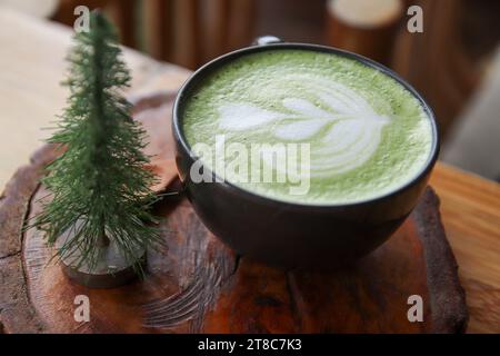 Tasse grüner Milchtee auf einem Holzständer Stockfoto
