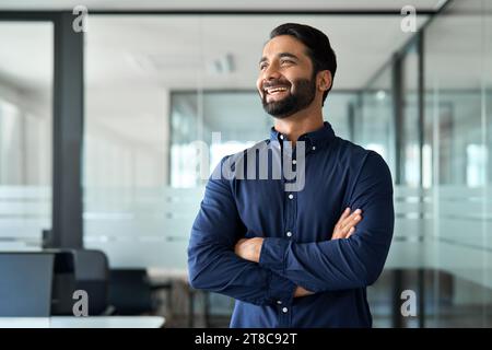 Glücklicher, selbstbewusster indischer Geschäftsmann, der im Amt wegblickt. Stockfoto
