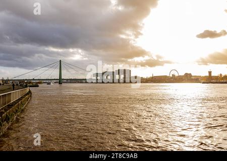 Rhein Hochwasser in Köln beim Pegel von 693 cm aus Sicht des Deutzer Rheinufers Höhe der Deutzer Brücke. mit Blick auf den Rheinauhafen mit ihren markanten Kranbauten bei Sonnenuntergang. 19.11.2023 Köln Deutz NRW Deutschland *** Rheinflut in Köln bei einem Wasserstand von 693 cm vom Deutz-Ufer auf Höhe der Deutz-Brücke mit Blick auf den Rheinauhafen mit seinen markanten Kranbauten bei Sonnenuntergang 19 11 2023 Köln Deutz NRW Deutschland Credit: Imago/Alamy Live News Stockfoto