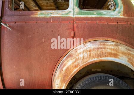 Die Hintertür auf der Fahrerseite und der Radkasten eines rostigen antiken Autos Stockfoto