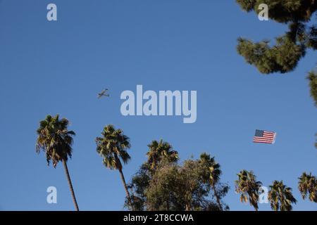 Ein kleines Flugzeug, das während eines Überflugs bei der Long Beach Veterans Day Celebration in Long Beach, CA USA, eine amerikanische Flagge über den Himmel zieht Stockfoto