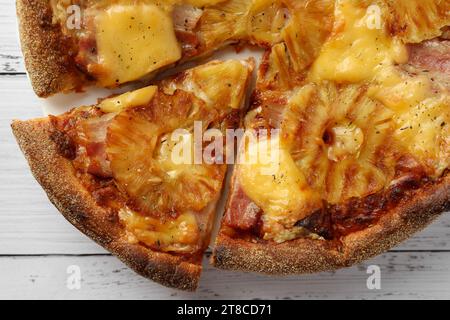 Köstliche hawaiianische Pizza mit Ananas auf weißem Holztisch, Blick von oben Stockfoto