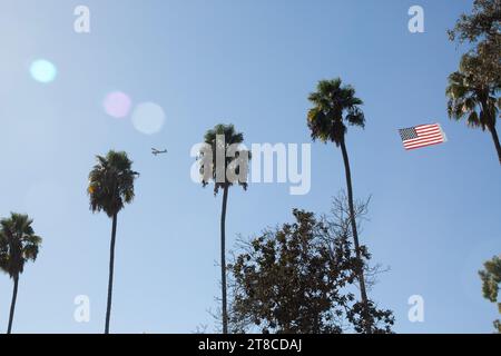 Ein kleines Flugzeug, das während eines Überflugs bei der Long Beach Veterans Day Celebration in Long Beach, CA USA, eine amerikanische Flagge über den Himmel zieht Stockfoto