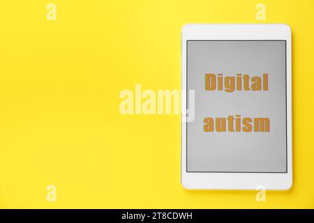 Tablet mit Phrase Digital Autism auf gelbem Hintergrund, Draufsicht und Platz für Text. Suchtverhalten Stockfoto