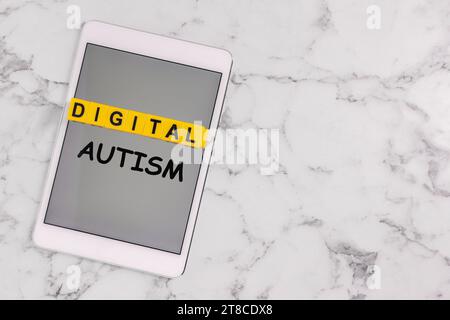 Suchtverhalten. Phrase Digital Autismus aus gelben Würfeln und Tablette auf weißem Marmortisch, Blick von oben. Leerzeichen für Text Stockfoto
