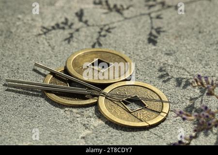 Akupunkturnadeln und alte Münzen auf Steinoberfläche Stockfoto