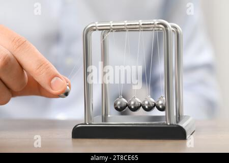 Mann, der mit Newtons Wiege am Tisch spielt, Nahaufnahme. Physikalisches Gesetz der Energieeinsparung Stockfoto