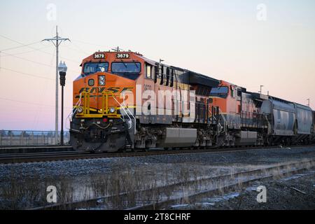 Stanwood, WA, USA – 17. November 2023; BNSF-Güterzug in Stanwood Washington bei Sonnenaufgang mit Logo auf orangefarbener Lokomotive Stockfoto