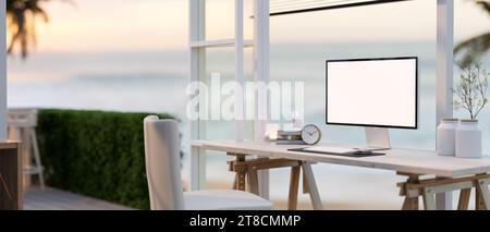 Ein gemütlicher, minimalistischer Heim-Arbeitsplatz mit einem Computermockup auf weißem Bildschirm auf einem Tisch vor dem Fenster. Home Workspace. 3D-Rendering, 3D-Abbildung Stockfoto