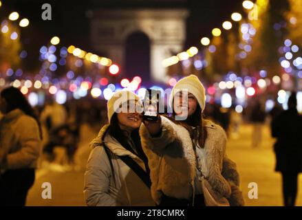 Paris, Frankreich. November 2023. In Paris, Frankreich, am 19. November 2023, machen die Menschen Selfies an der Champs-Elysees-Avenue, beleuchtet von Weihnachtslichtern. Die jährliche Weihnachtsfeier fand hier am Sonntag statt. Quelle: Gao Jing/Xinhua/Alamy Live News Stockfoto