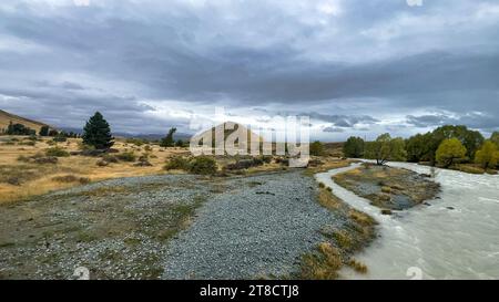 Überfluteter Bach auf der kurvenreichen Schotterstraße zwischen Lake Tekapo und Lake Pukaki in ländlichem Ackerland Stockfoto