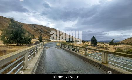 Überfluteter Bach auf der kurvenreichen Schotterstraße zwischen Lake Tekapo und Lake Pukaki in ländlichem Ackerland Stockfoto