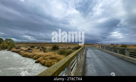 Überfluteter Bach auf der kurvenreichen Schotterstraße zwischen Lake Tekapo und Lake Pukaki in ländlichem Ackerland Stockfoto