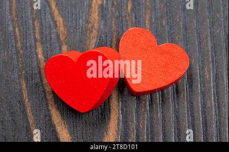 Zwei rote handgemachte hölzerne geschnitzte Herzen auf Holz Hintergrund, Paar Beziehung Valentinstag-Konzept Stockfoto