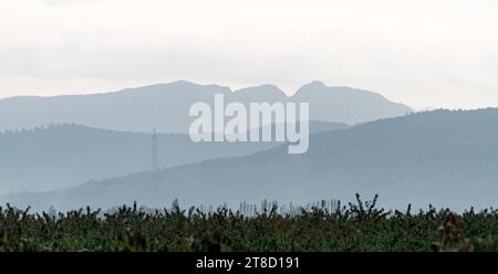 Weites Panorama von Bergsilhouetten und gepflügtem Bauernhof Stockfoto