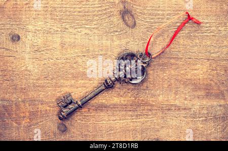 Alte Schlüssel auf hölzernem Hintergrund mit Band Stockfoto
