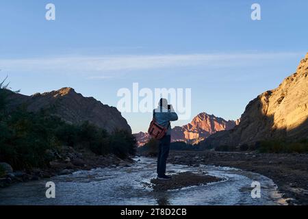 Rückansicht eines asiatischen Fotografen, der einen Sonnenaufgang am mysteriösen Grand Canyon von Tianshan in Xinjiang, China, fotografiert Stockfoto
