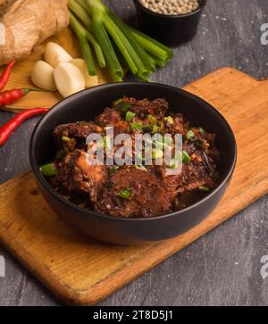 Geschnittenes geröstetes Rindfleischfutter, geröstetes Rindfleisch Lauch schwarze Schüssel auf schwarzem Hintergrund. Stockfoto