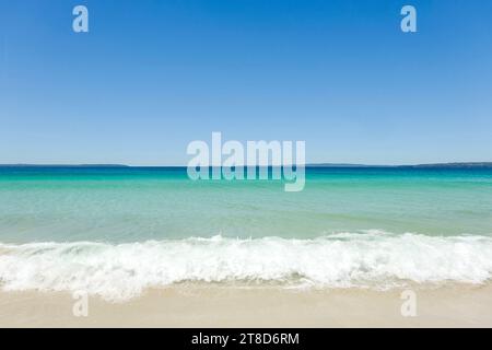 Klares türkisfarbenes Wasser, wolkenloser blauer Himmel und Meeresschaum an einem sonnigen Tag am Callala Beach in Shoalhaven – Jervis Bay National Park, NSW Stockfoto