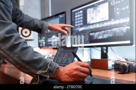 Asiatischer männlicher Schöpfer, arbeitet mit Filmmaterial oder Video auf seinem PC in seinem kreativen Bürostudio. Stockfoto