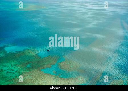 Ein Blick aus der Vogelperspektive auf ein Boot, das über die Korallenriffe und das türkisfarbene Wasser des äußeren Great Barrier Reef fährt Stockfoto