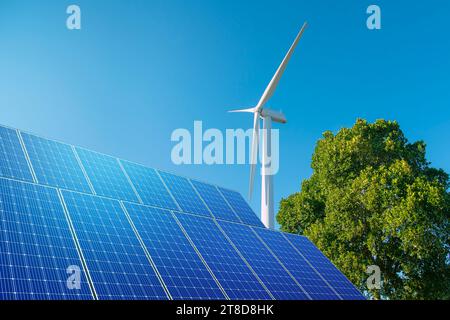 Windkraftanlage mit Solarpaneelen am blauen Himmel. Konzept der sauberen Energie. Energieversorgung, Windkraftanlage, Äolische Turbine, Energieverteilung. Stockfoto