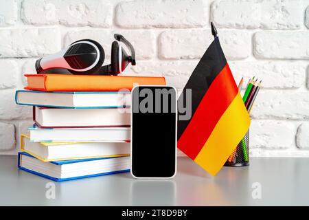 Stapel Bücher und Flagge Deutschlands auf dem Schreibtisch. Deutschsprachenlernkonzept Stockfoto