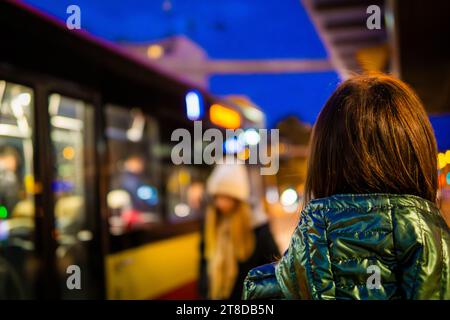 Frau, die am späten Abend auf einen Bus wartet, verschwommener Hintergrund, Silhouette Stockfoto