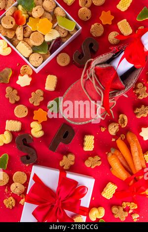 Sinterklaas, St. Nikolaus Tag Hintergrund. Kleiner roter Schuh mit Karotten und Süßigkeiten, Trooigos, Pepernoten, Süßigkeiten. Niederländische Weihnachtsfeiertage grüßet Stockfoto