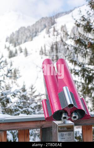 Münzferngläser für Touristen auf einer verschwommenen Schneelandschaft in Saalbach Hinterglemm, Österreich Stockfoto