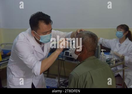 Phnom Penh, Kambodscha. November 2023. Ein chinesischer Arzt (L) untersucht am 14. November 2023 in einem Krankenhaus in der Provinz Prey Veng in Kambodscha einen Patienten, der an Katarakt leidet. Das von der chinesischen GX Foundation finanzierte Projekt zur Beseitigung der Kataraktblindheit für den Zeitraum von 2022 bis 2025 wird voraussichtlich 10.000 Kataraktpatienten in der Provinz Prey Veng wieder sehen. ZUM THEMA „Feature: Chinesische Ärzte helfen bei der Wiederherstellung des Sehvermögens von Kataraktpatienten in Kambodscha“ Kredit: Liao Hongqing/Xinhua/Alamy Live News Stockfoto