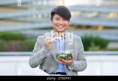 Koreanischer Unternehmer genießt Salat inmitten der Stadt Stockfoto