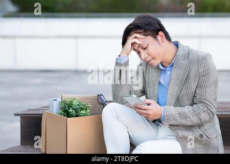 Ein gefeuerter japanischer Büroangestellter hält Telefon in der Stadt Stockfoto