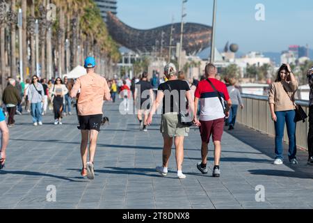 Barcelona, Spanien: 19. November 2023: People Wal k Barceloneta Beach mit Frank Gehrys Peix d'Or (Walskulptur) im Winter 2023. Stockfoto