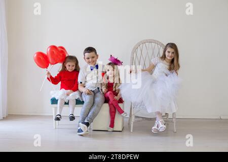 Wunderschöne Kinder mit roten Bällen, die auf Stühlen sitzen Stockfoto