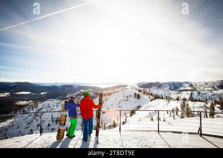 Skifahrer und Snowboarder genießen die Aussicht vom Gipfel eines Berges. Stockfoto