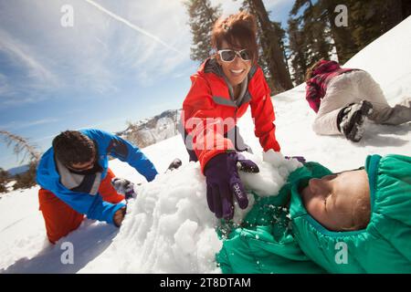 Familie spielt im Schnee in einem Skigebiet. Stockfoto